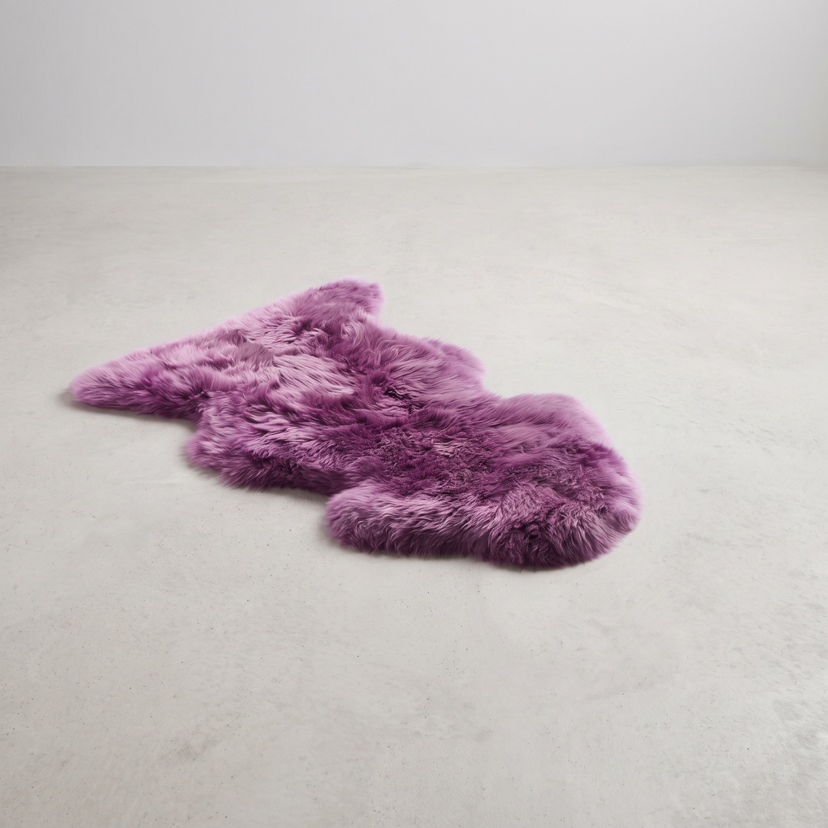 Medici purple single sheepskin rug laid flat on a pale grey floor