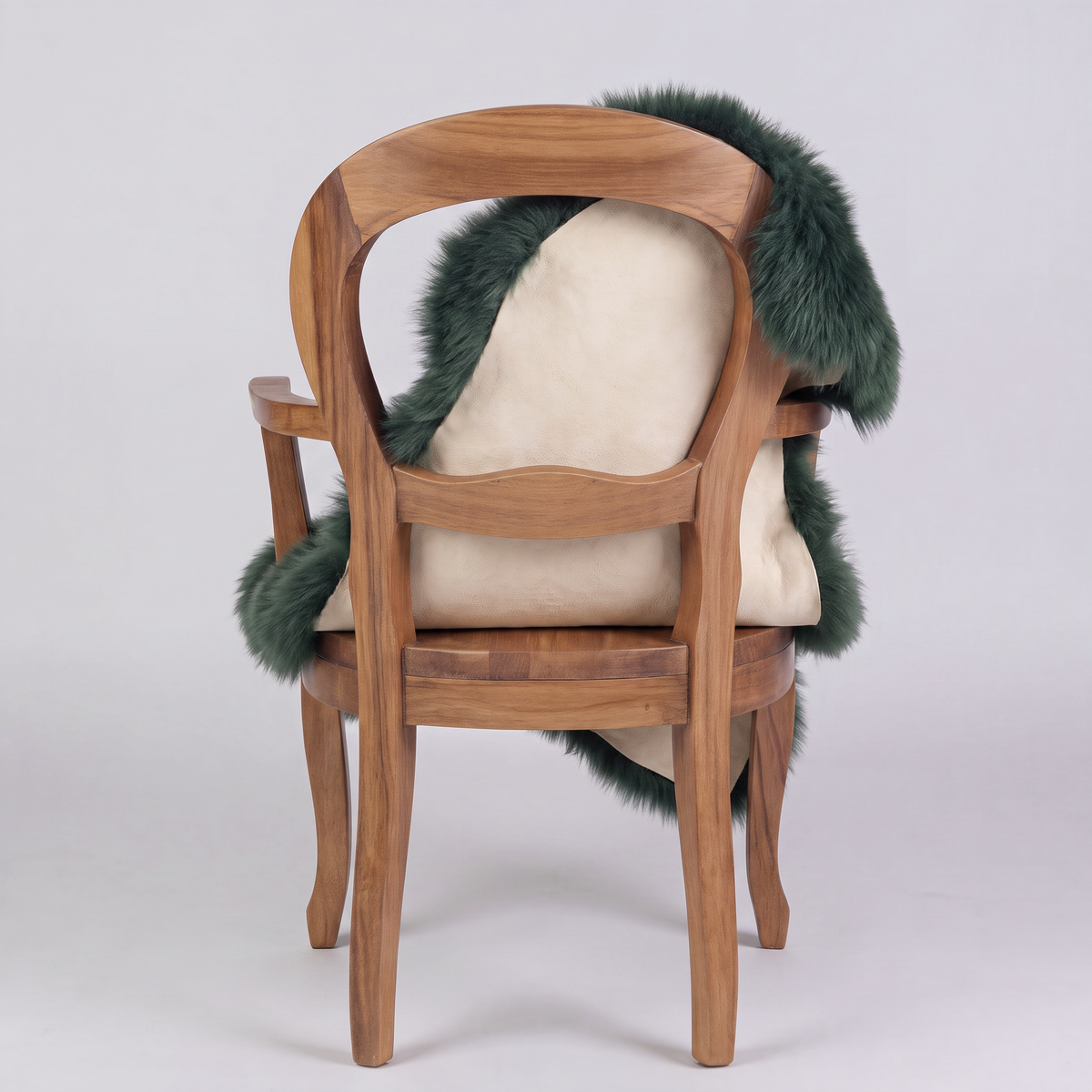 Jungle Green single sheepskin rug over the back of a wooden armchair, rear view