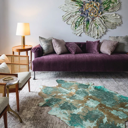 Teal acid wash cowhide rug styled in front of a plum velvet sofa in an elegant pale-grey living room