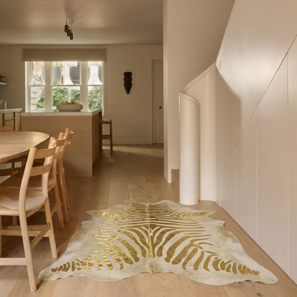 Gold zebra metallic cowhide rug styled on the oak floor of a bright open-plan kitchen hallway