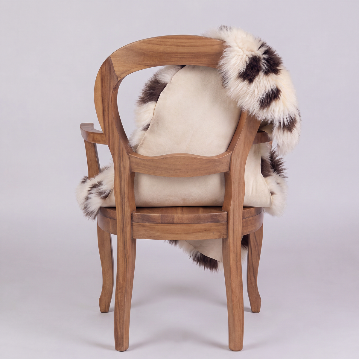 Printed Jacob single sheepskin rug over the back of a wooden armchair, rear view