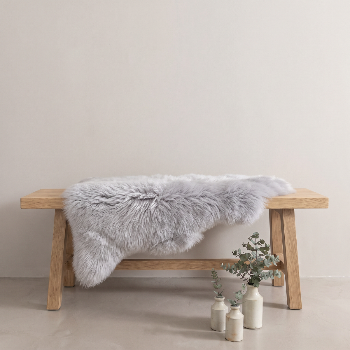 Light Grey sheepskin rug draped over an oak bench in a minimal interior