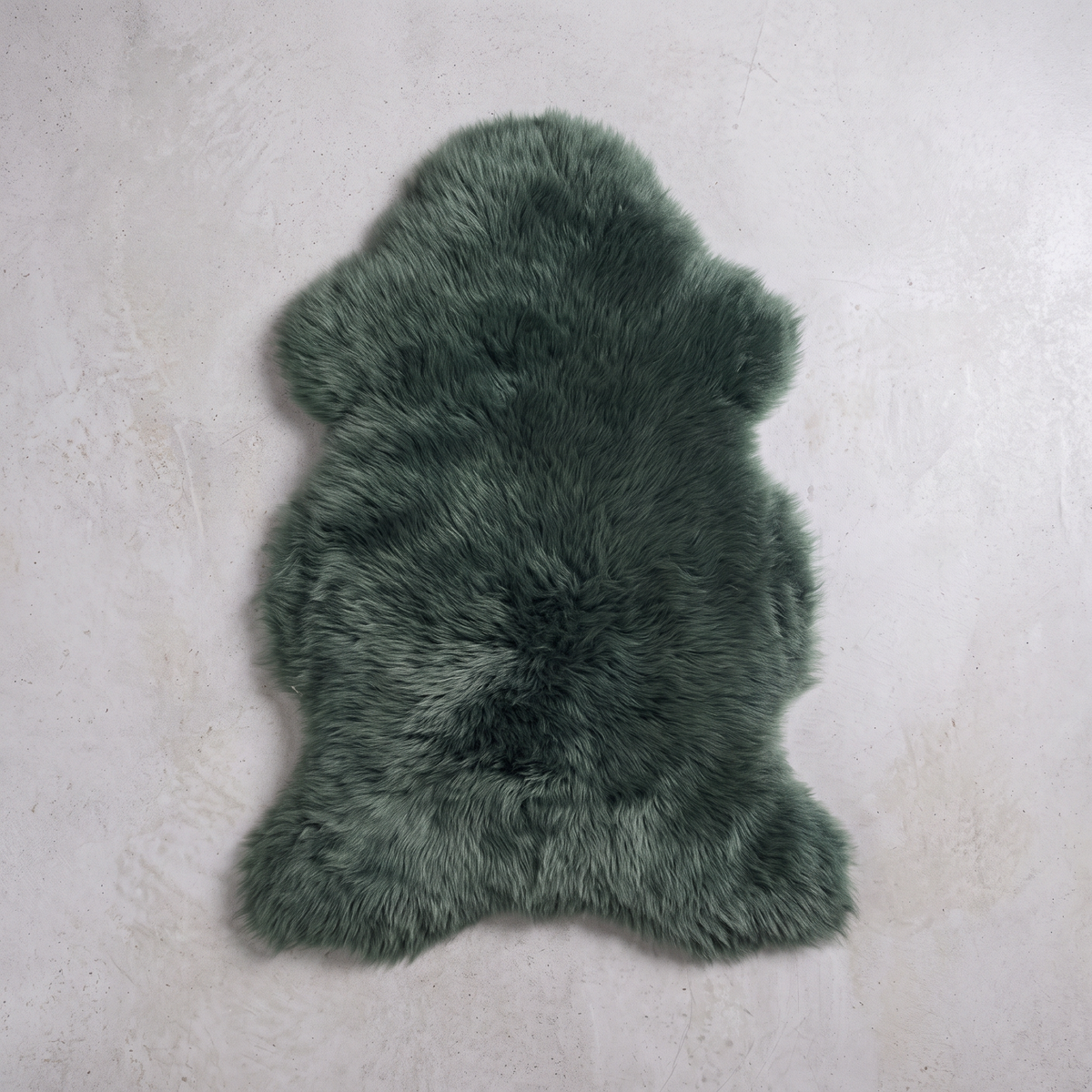 Jungle Green single sheepskin pelt flat-lay on a pale grey floor
