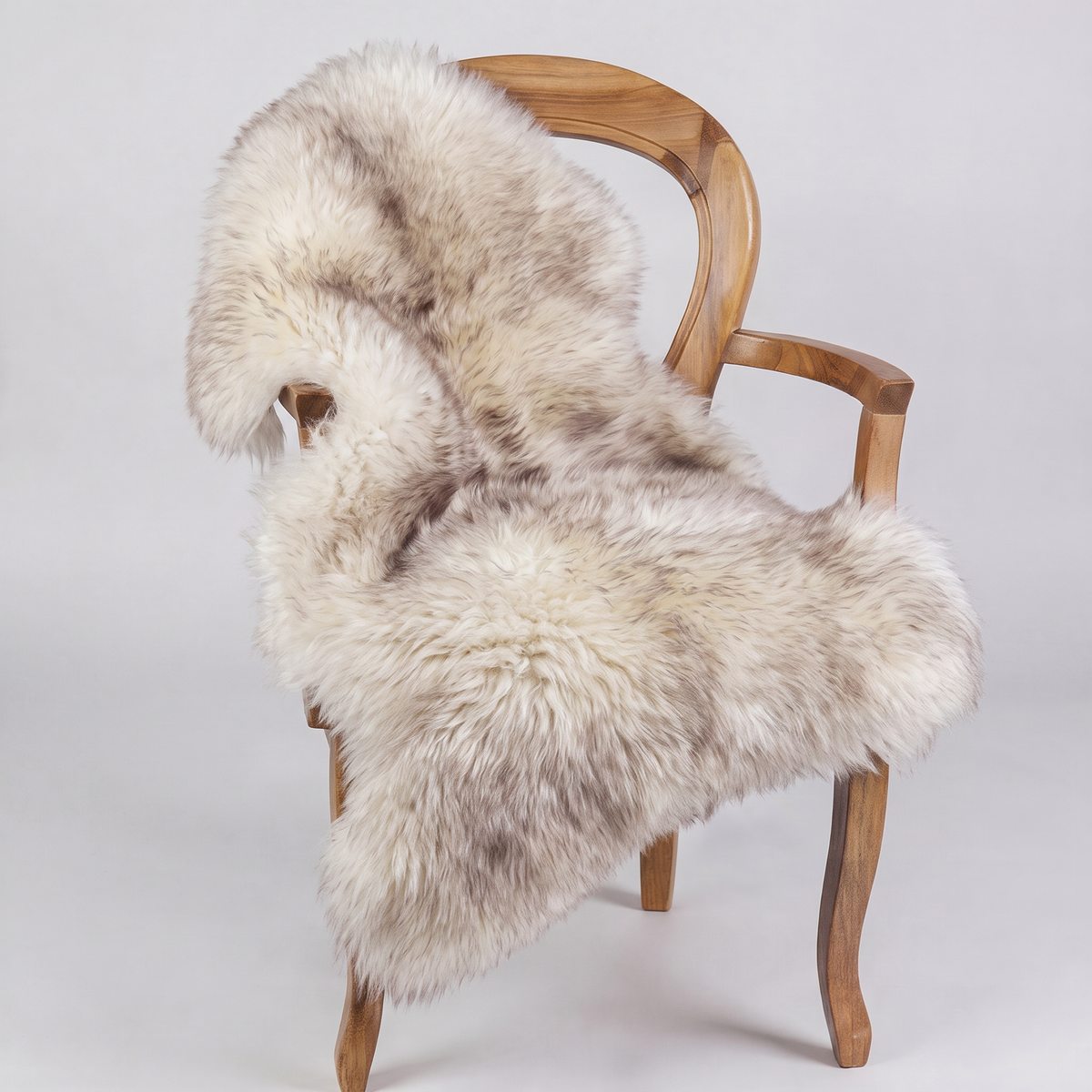 Wolf Tip sheepskin rug draped over a wooden armchair, front three-quarter view