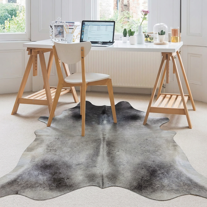 Grey cowhide rug styled under a trestle desk in a bright Scandinavian home office