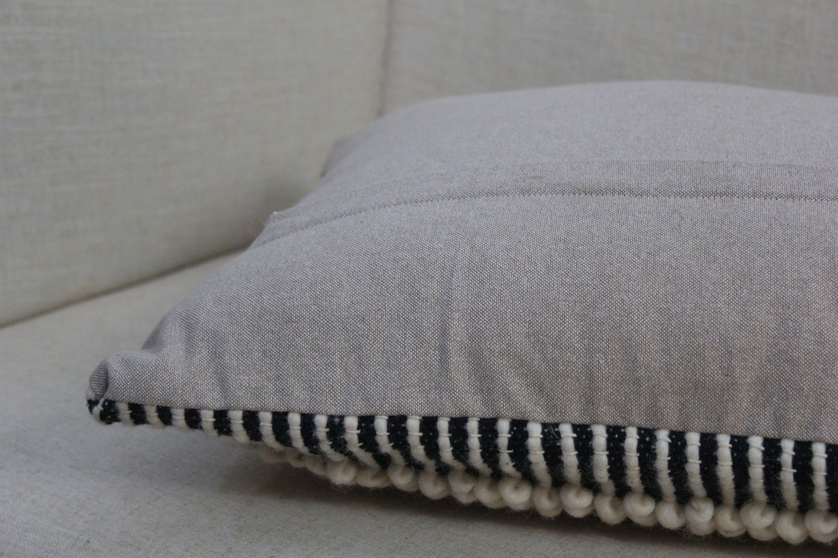 Back of the Salt & Pepper wool cushion cover in plain grey cotton, with the striped wool edge visible