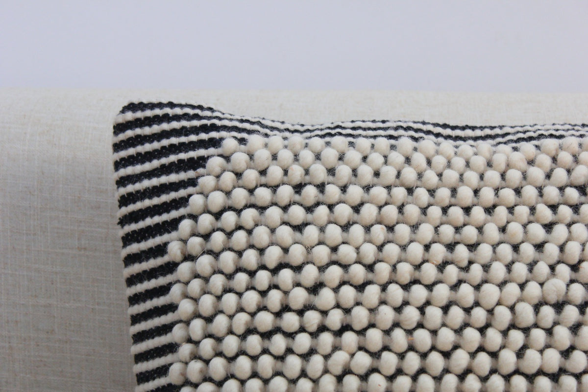 Corner close-up of the Salt & Pepper wool cushion showing hand-woven ivory bobbles meeting the black-and-white stripe border