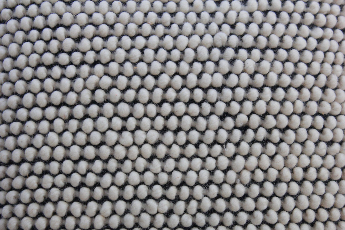 Detail of the Salt & Pepper cushion's raised ivory wool bobble texture over a black weave