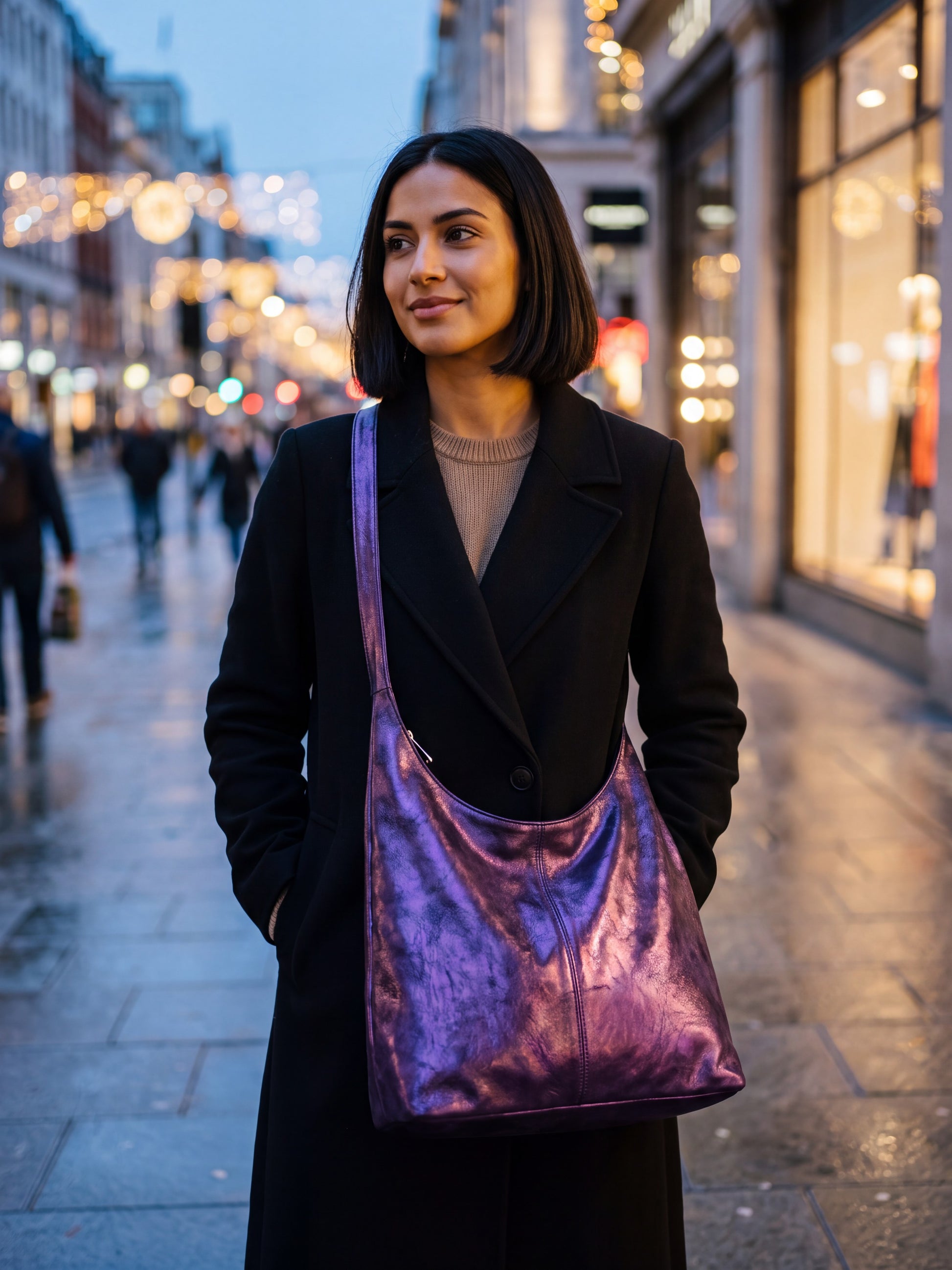 Woman carrying the Violet Silvia Metallic Suede Slouch Bag on a city street at evening