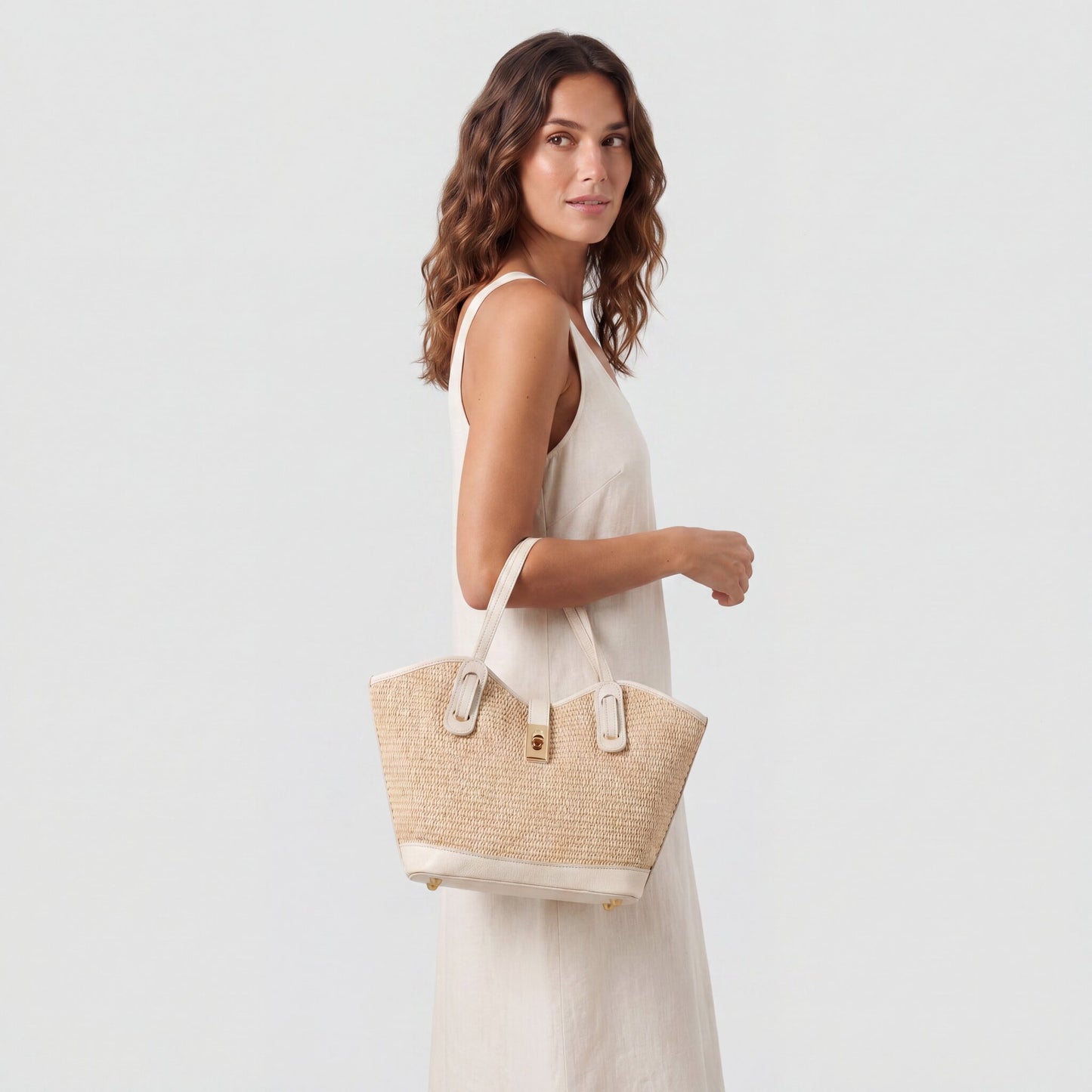 Model carrying the Oyster Sorrento Raffia & Leather Tote from the crook of her elbow, studio shot