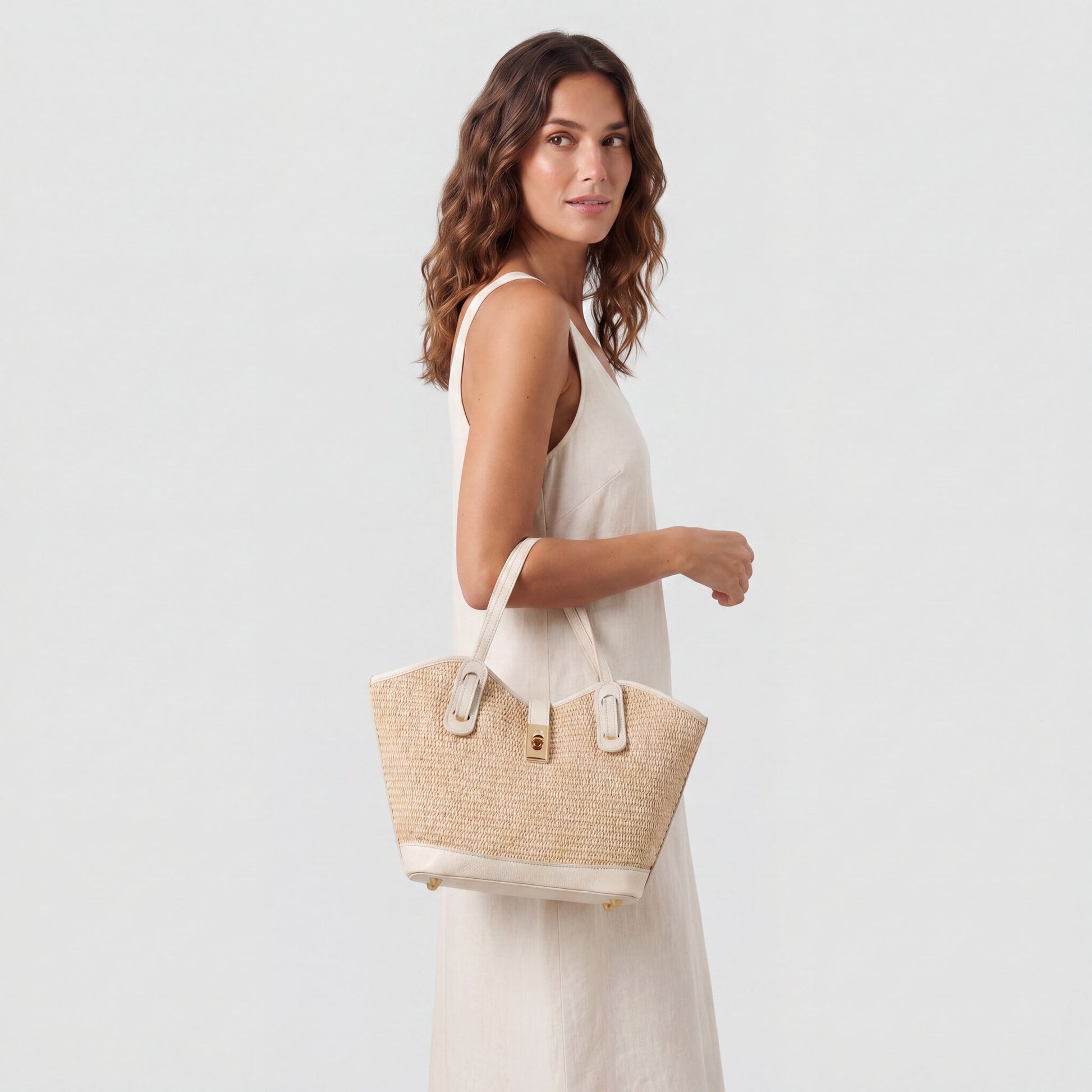 Model carrying the Oyster Sorrento Raffia & Leather Tote from the crook of her elbow, studio shot
