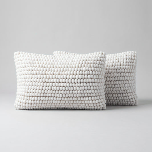 Pair of natural ivory wool lumbar cushion covers, 30 x 50 cm, with hand-felted wool balls, on a light grey studio background