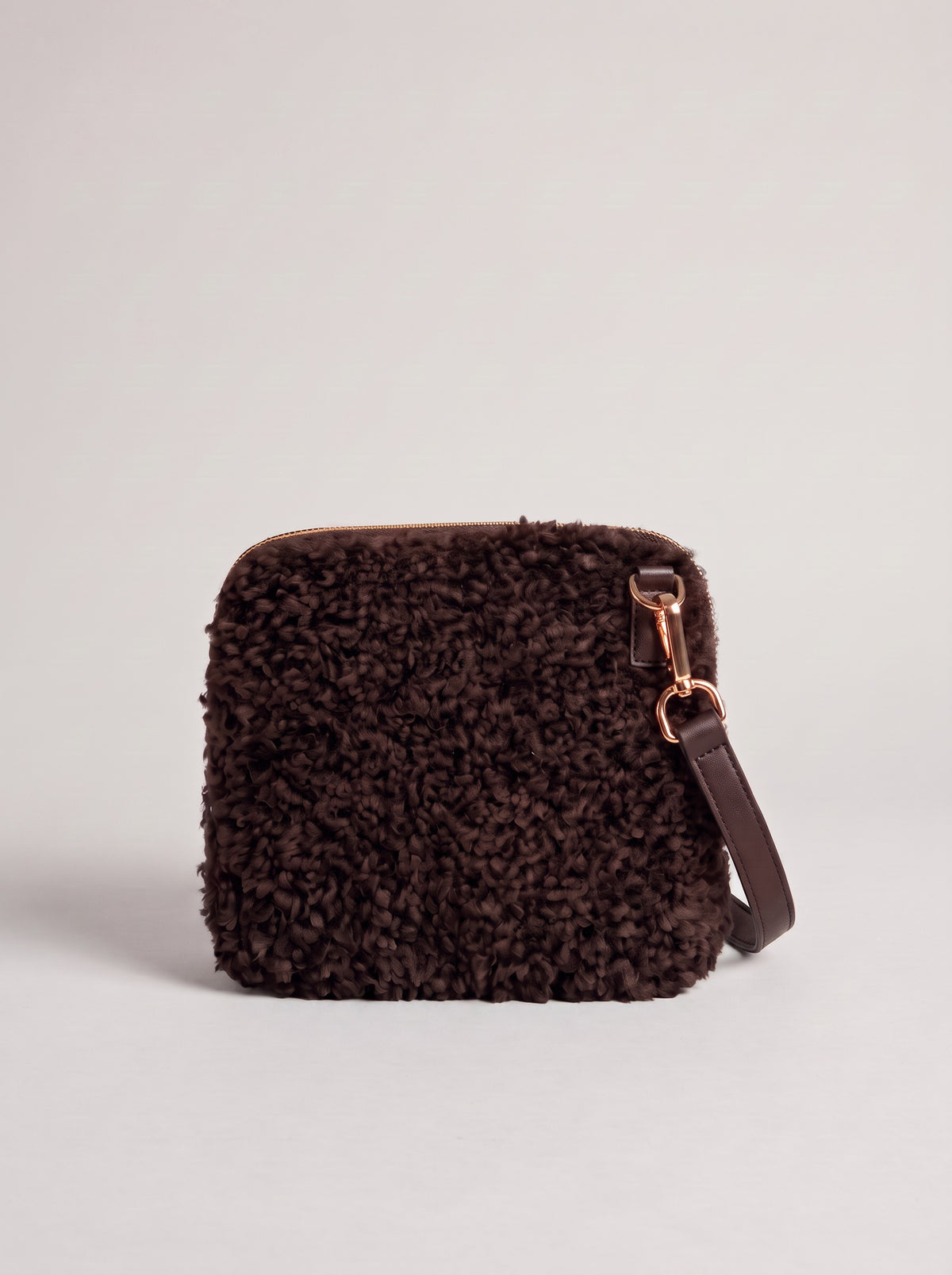Zita faux shearling crossbody bag in dark chocolate on a light grey studio background