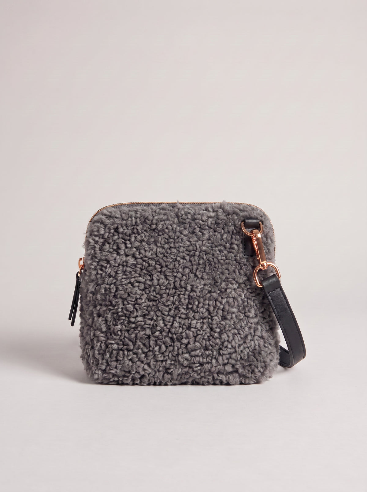 Zita faux shearling crossbody bag in grey with black leather strap, on a light grey studio background