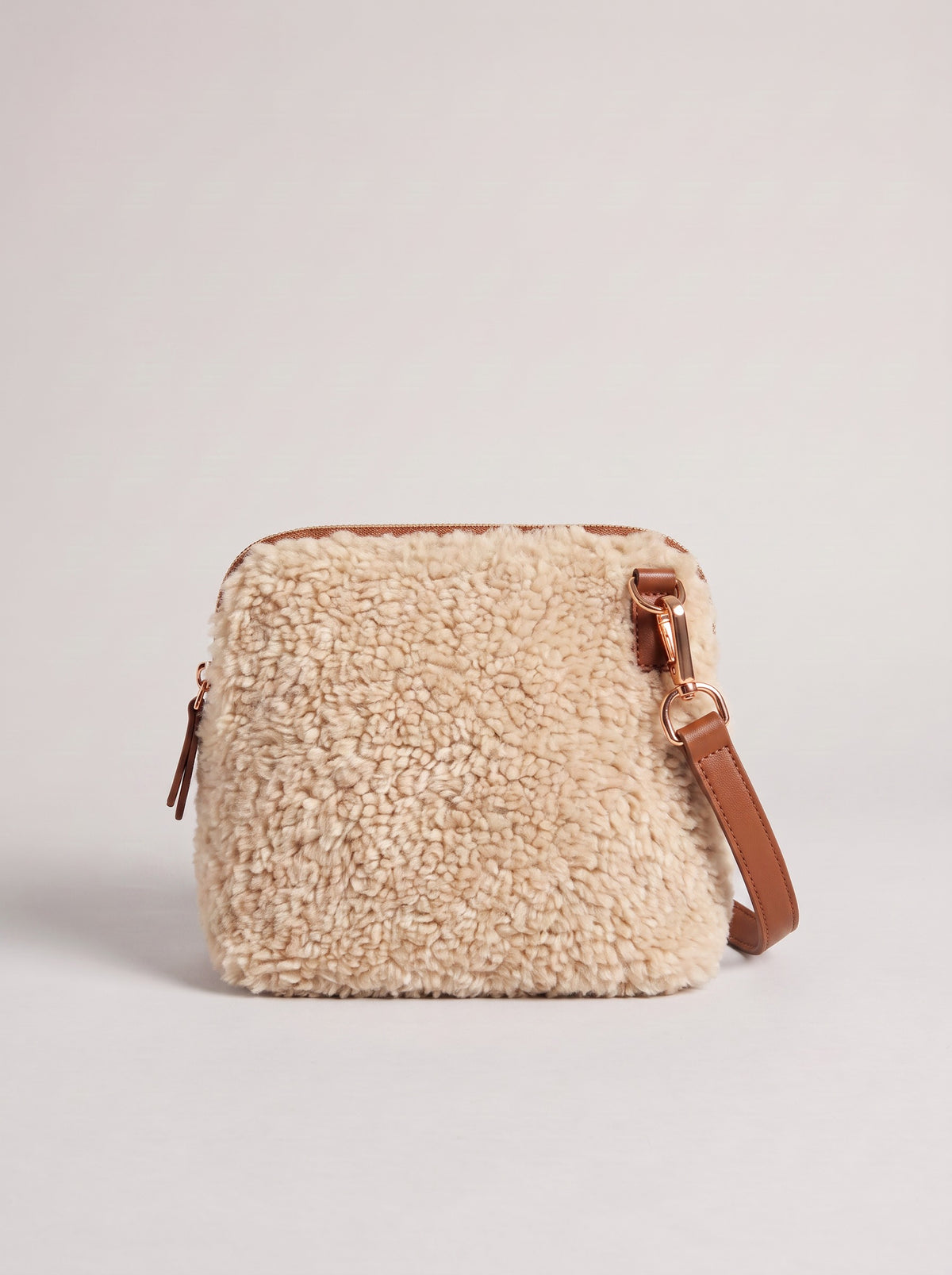Zita faux shearling crossbody bag in oyster with brown leather strap, on a light grey studio background