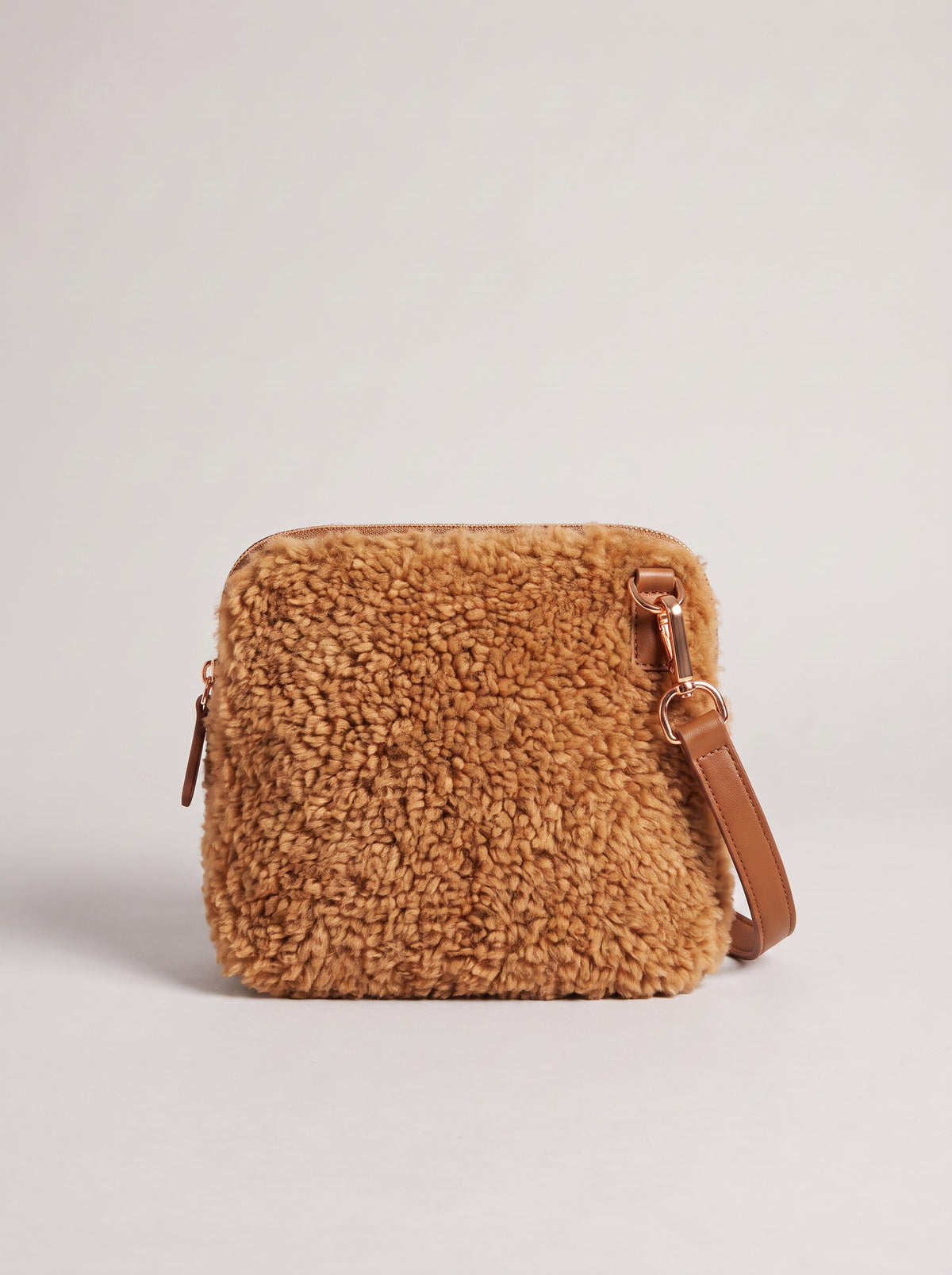 Zita faux shearling crossbody bag in tan on a light grey studio background